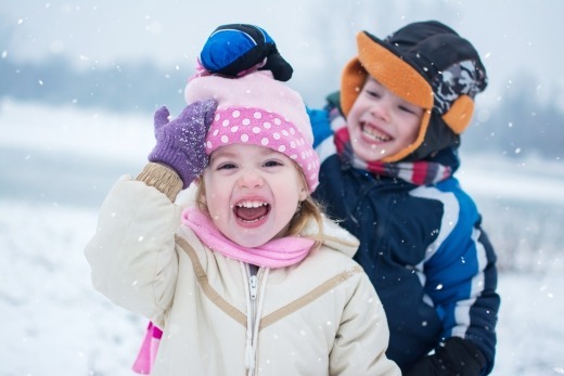 Jongetje en meisje lachend in de sneeuw